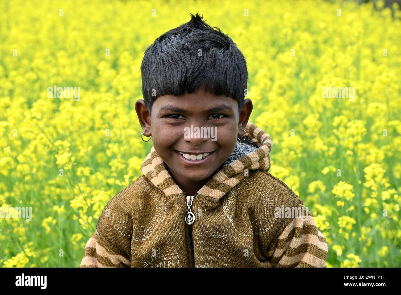 Il ragazzo remoto del villaggio che si diverte nel campo di coltivazione dei fiori di senape nel Bengala Occidentale, in India. Foto Stock