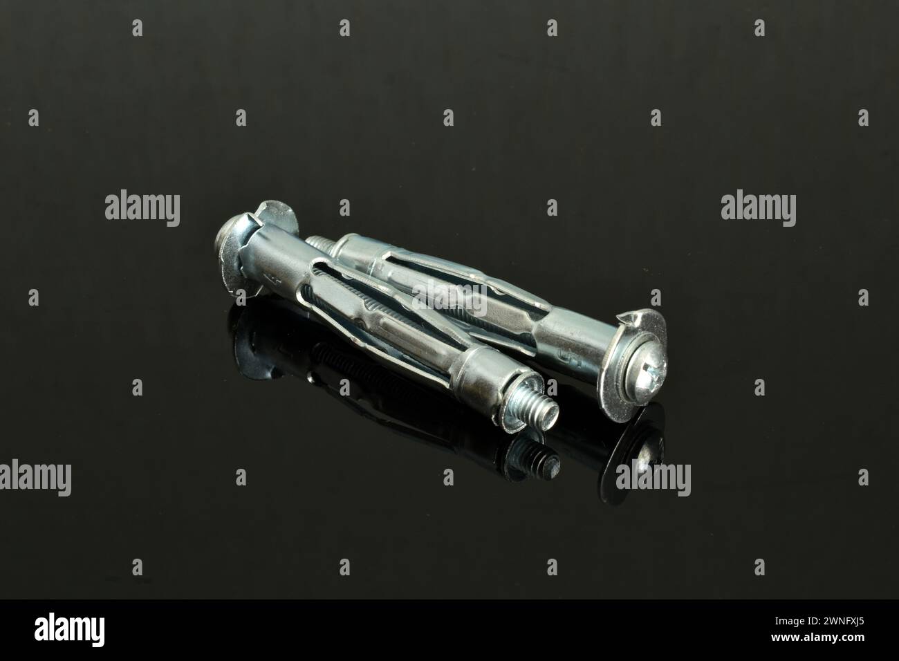 Diversi tasselli di ancoraggio, argento, primi piani, si trovano su uno sfondo scuro. Foto Stock