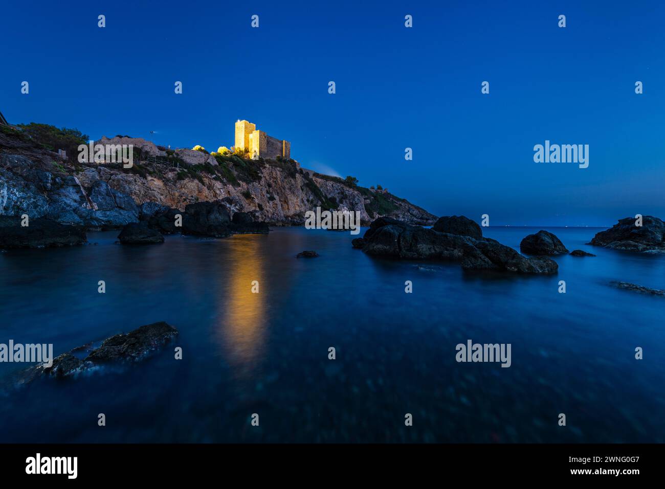 Il castello di Rocca Aldobrandesca sulla costa rocciosa della Maremma a Talamone al crepuscolo, Toscana, Italia Foto Stock