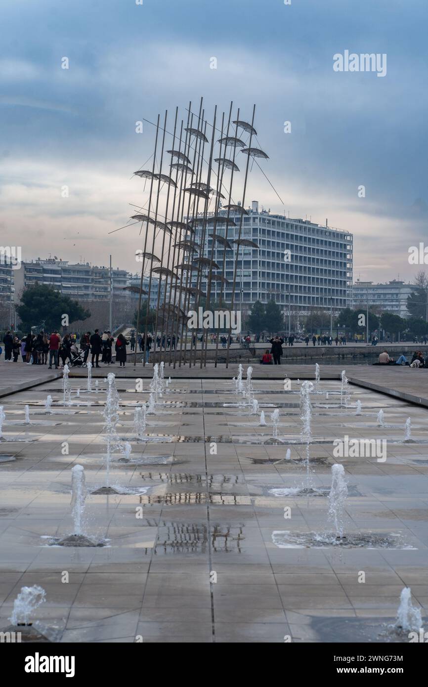 Baldacchino dinamico. Scultura a ombrello di George Zongolopoulos tra fontana, superficie bagnata e folle. Il cielo è spettacolare. 2,10. Salonicco Grecia 2024 Foto Stock
