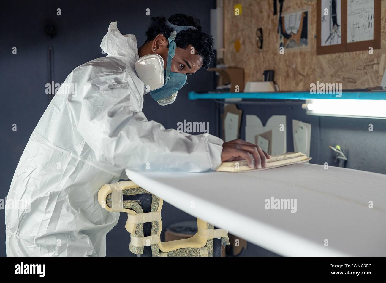 Produzione di tavole da surf, Shaper che lavora sui dettagli della tavola. Concetto di produzione industriale, professionale qualificata, professione e occupazione. Foto Stock