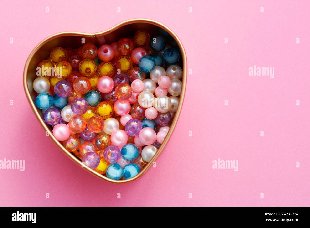 Contenitore a forma di cuore contenente perle colorate per realizzare bracciali e collane Foto Stock