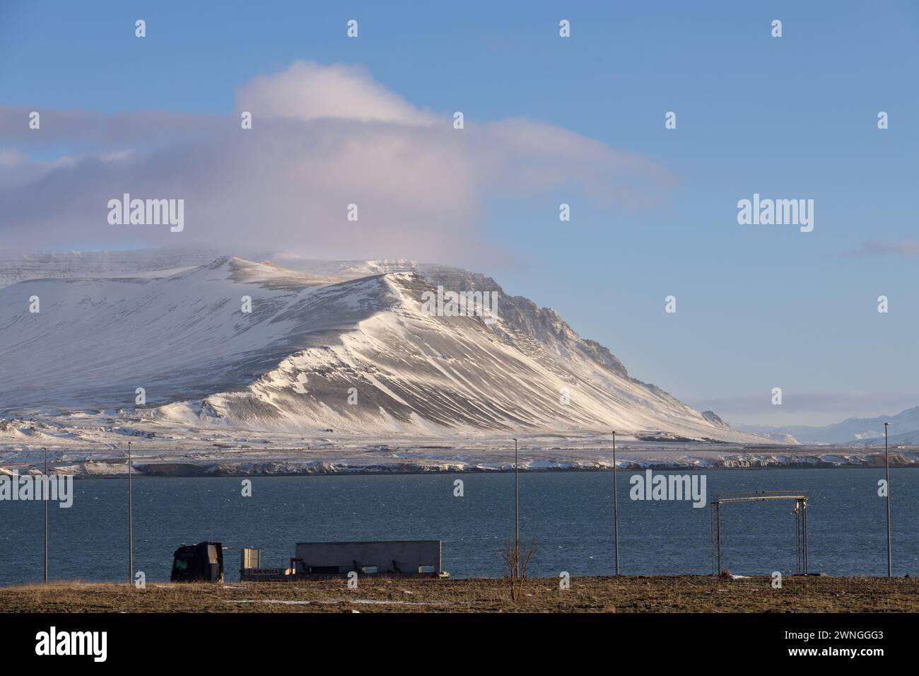 Guida di un camion di fronte al mare con montagna sullo sfondo, Islanda - febbraio 2024 Foto Stock