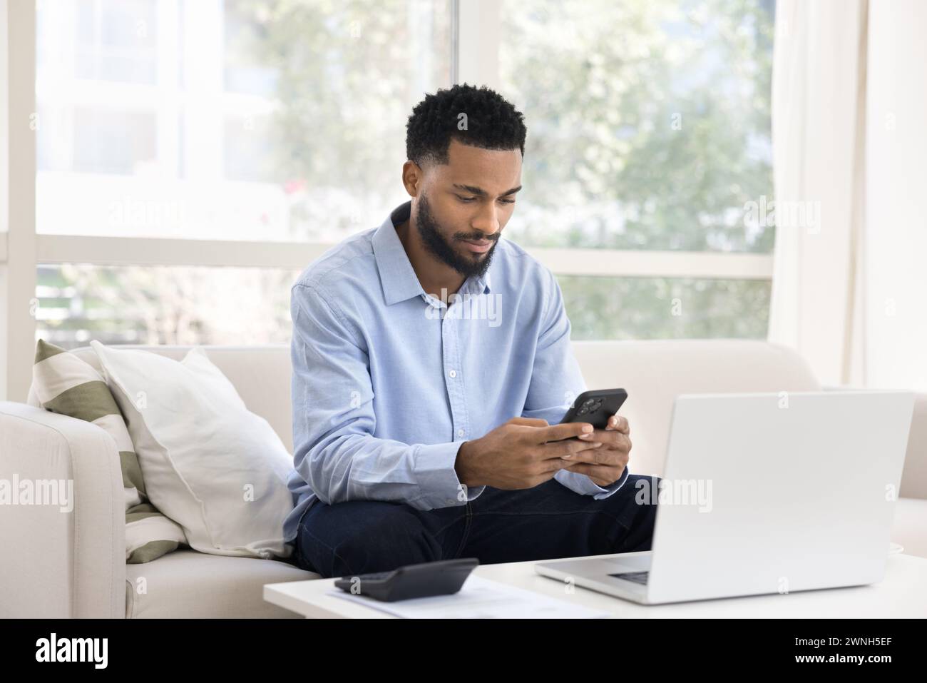 Un giovane africano concentrato che fa un lavoro di contabilità a casa Foto Stock