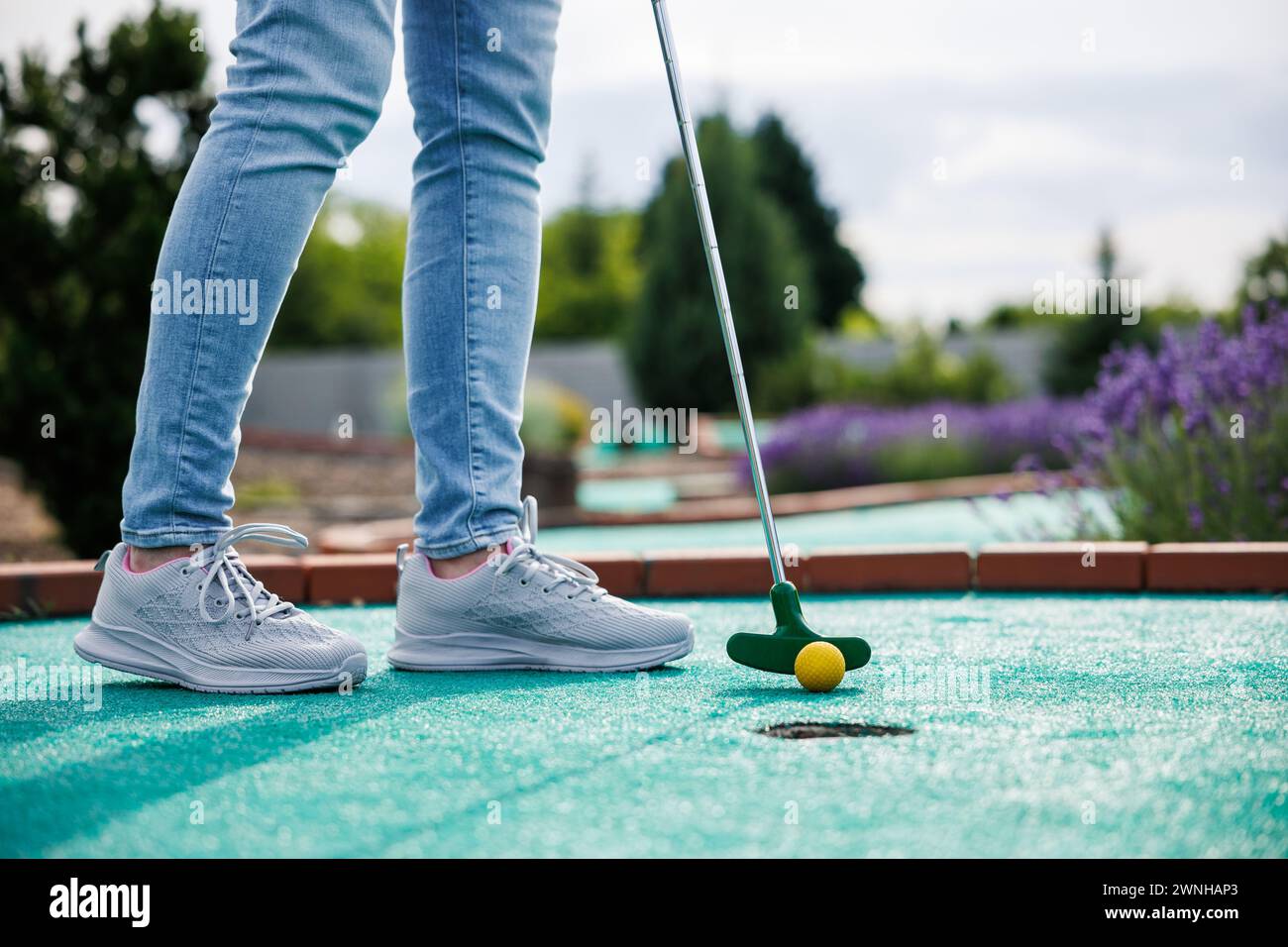 Golfista che gioca all'avventura o al minigolf e prova a mettere la palla nella buca. Attività sportive e ricreative Foto Stock