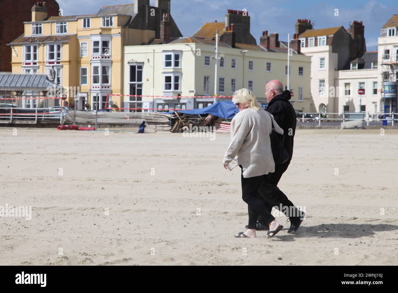 Una coppia di anziani che cammina sulla spiaggia sabbiosa di Weymouth, Dorset, Inghilterra, Regno Unito. Foto Stock