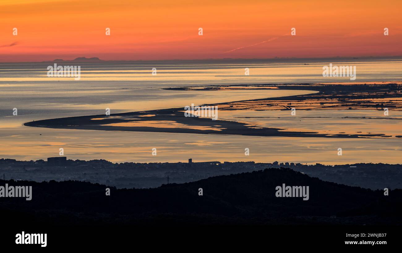 Alba su Punta del Fangar vista dal parco eolico Baix Ebre. Sullo sfondo, il Puig maggiore della catena montuosa Tramuntana di Maiorca. Spagna Foto Stock