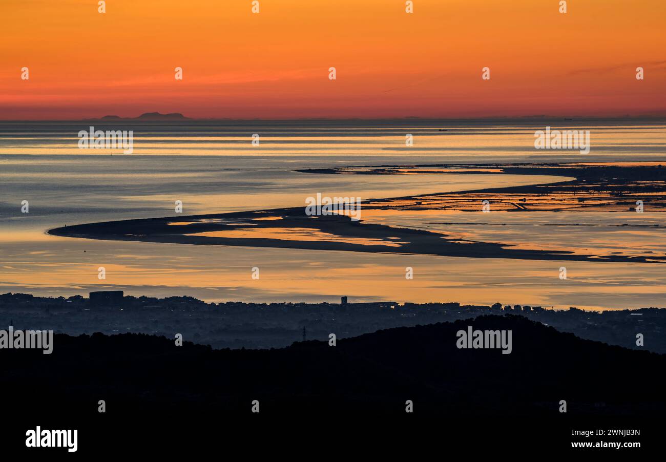 Alba su Punta del Fangar vista dal parco eolico Baix Ebre. Sullo sfondo, il Puig maggiore della catena montuosa Tramuntana di Maiorca. Spagna Foto Stock