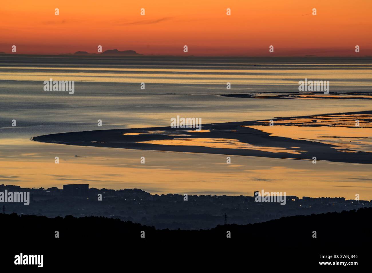 Alba su Punta del Fangar vista dal parco eolico Baix Ebre. Sullo sfondo, il Puig maggiore della catena montuosa Tramuntana di Maiorca, Spagna Foto Stock