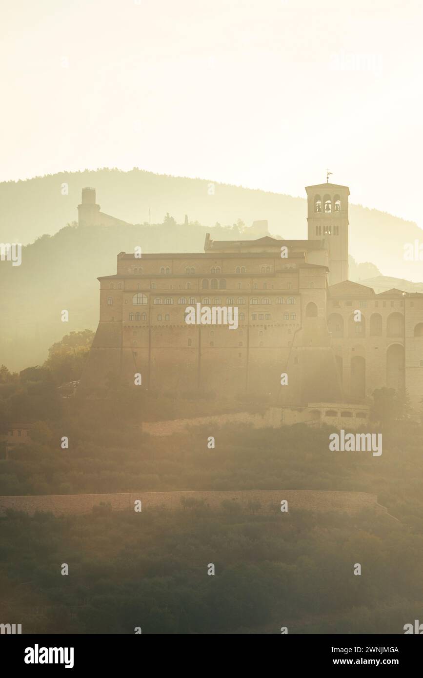 La Rocca maggiore, la basilica di San Francesco, la città vecchia di Assisi e il Monte Subasio retroilluminato dal sole del mattino, Umbria, Italia Foto Stock