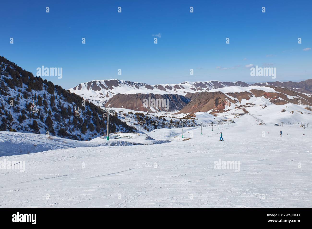 Ampia pista da sci presso il resort. Sciatori e snowboarder che scivolano lungo il pendio di una montagna innevata. Attività per le vacanze invernali, svago estremo. Inverno naturale Foto Stock