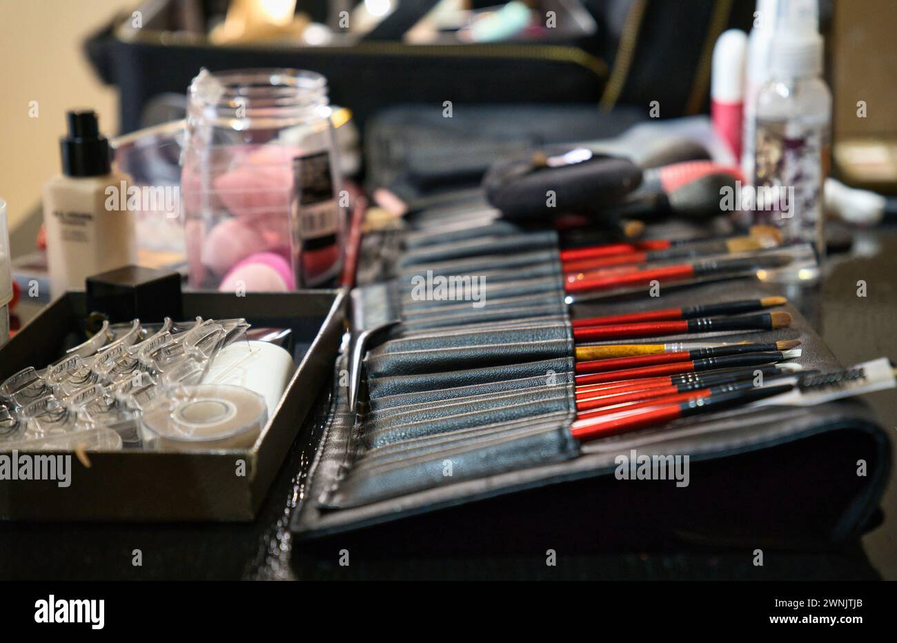 Cosmetici decorativi professionali, utensili per il trucco e accessori, disposti su un tavolo. Postazione di lavoro per make-up artist, scrivania, studio. Foto Stock