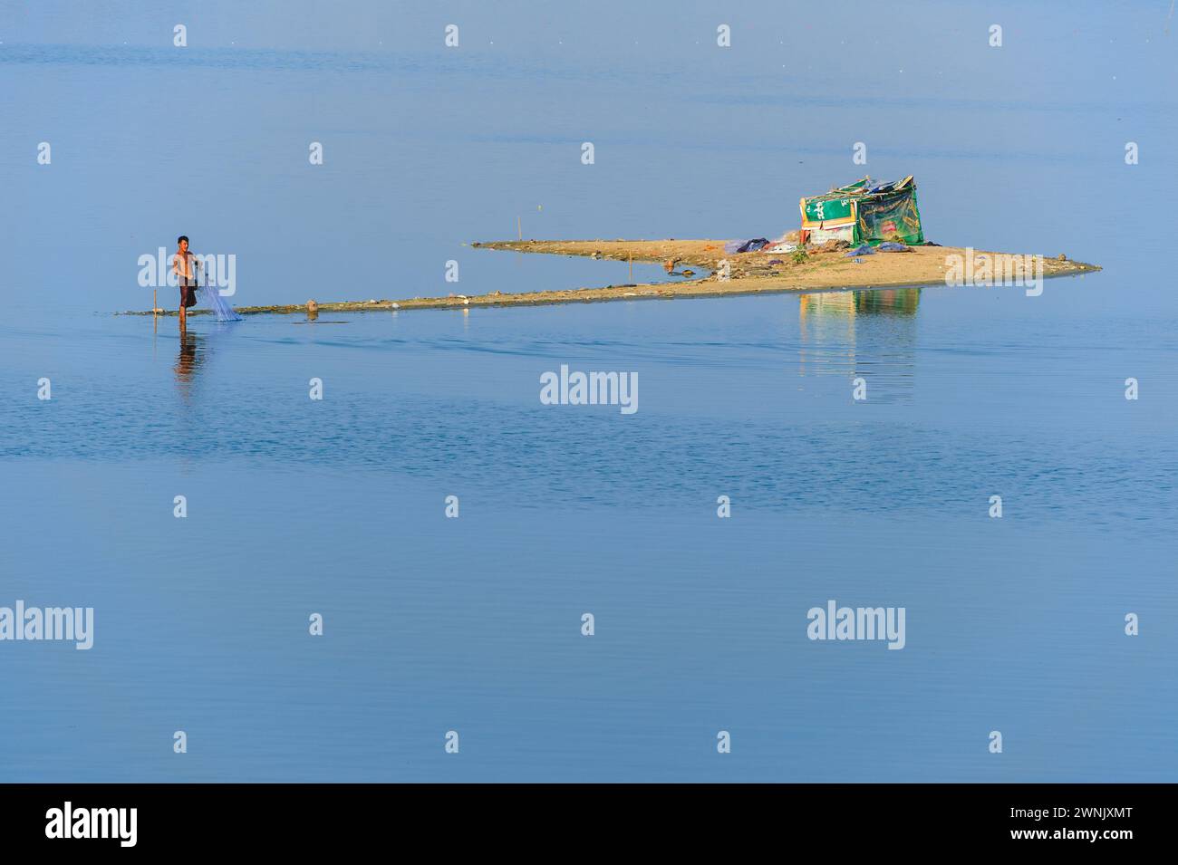 13 febbraio 2016: I pescatori preferiscono il wading Waist in profondità nelle acque fangose alla ricerca di pesci nel lago Taungthaman vicino ad Amarapura in Myanmar. Foto Stock