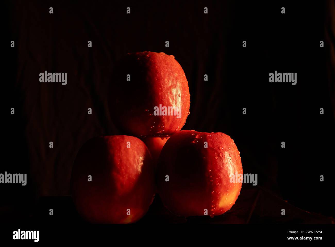 Tre mele con gocce d'acqua, sfondo nero, luce laterale Foto Stock