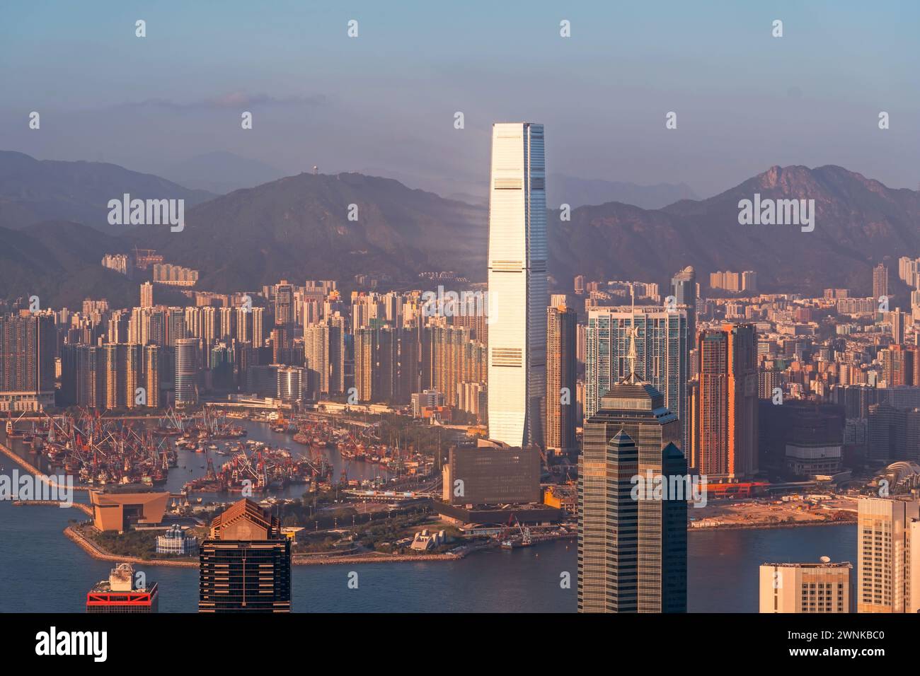 Vista panoramica della città di Hong Kong, moderna baia panoramica con chiatte da carico durante il tramonto di sera, incredibile luce dai toni caldi Foto Stock