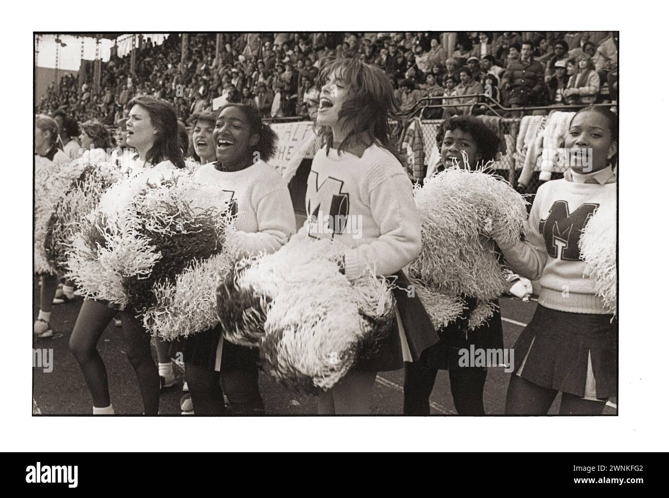 Le cheerleader delle scuole superiori scuotono i loro pom a una partita al Midwood Field di Brooklyn, New York. Non ne sono certo, ma credo che queste ragazze vengano dalla Midwood High. Foto Stock