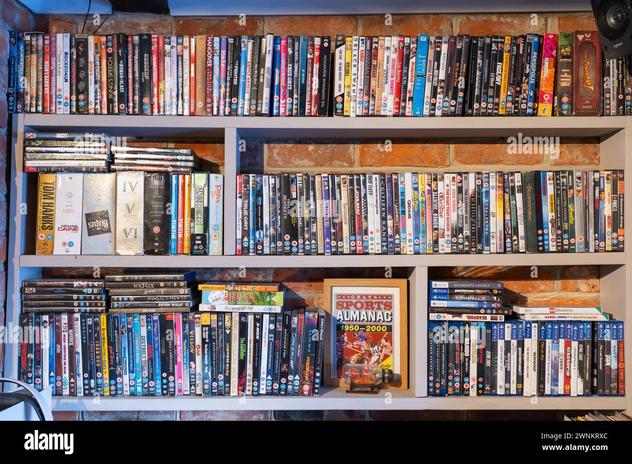 Collezione di DVD e custodie per videogiochi su scaffali in una sala/soggiorno del Regno Unito. Concetto: Supporti fisici, supporti retrò, spazio di archiviazione, ingombro domestico Foto Stock