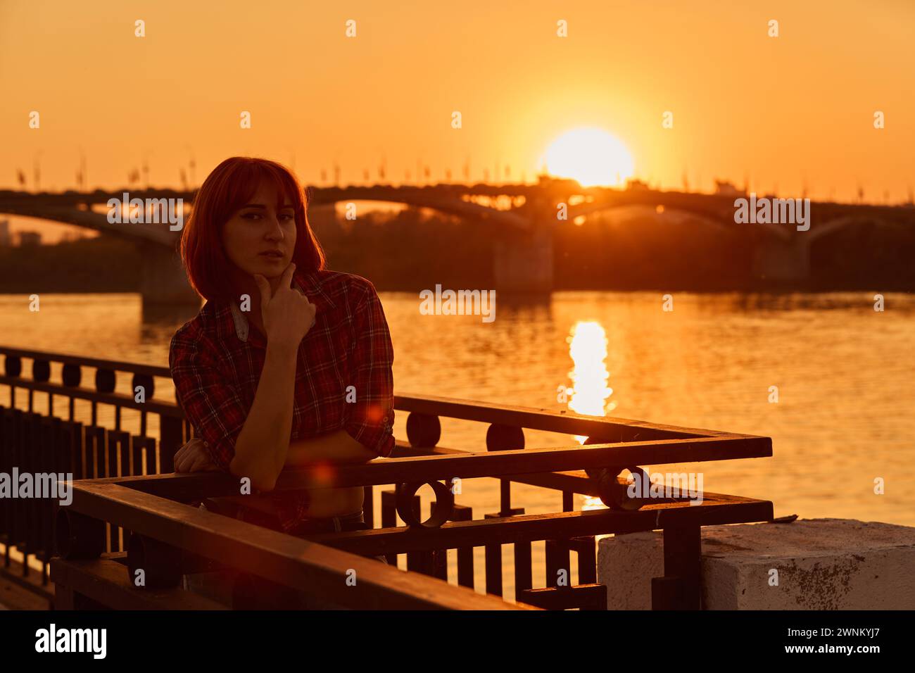 Primo piano ritratto di una giovane ragazza alla luce del sole. Città, ponte. Tramonto. Fiume Foto Stock