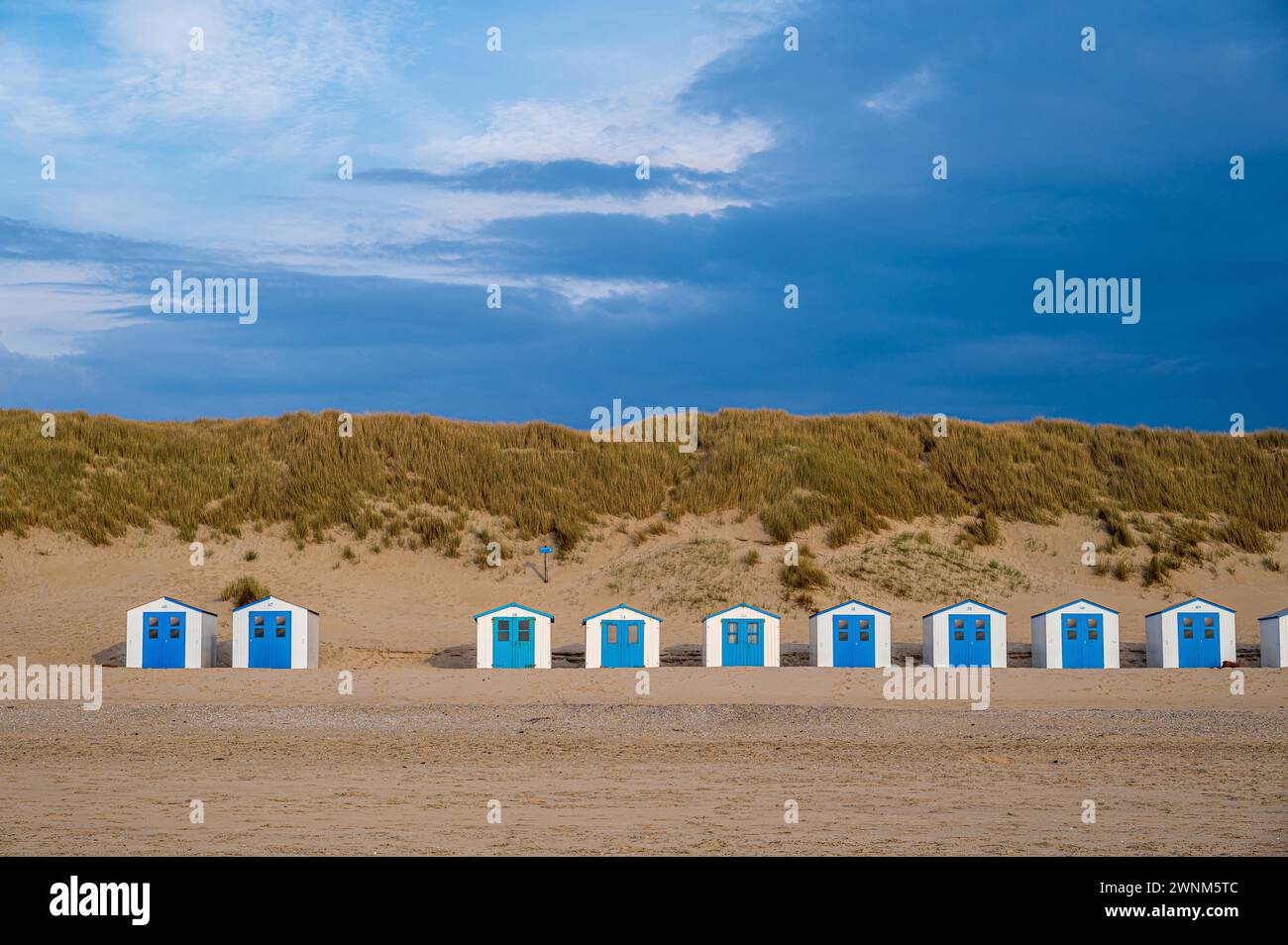 Case sulla spiaggia blu con dune sotto il cielo in luce dorata, Texel, Noord-Holland, Paesi Bassi Foto Stock