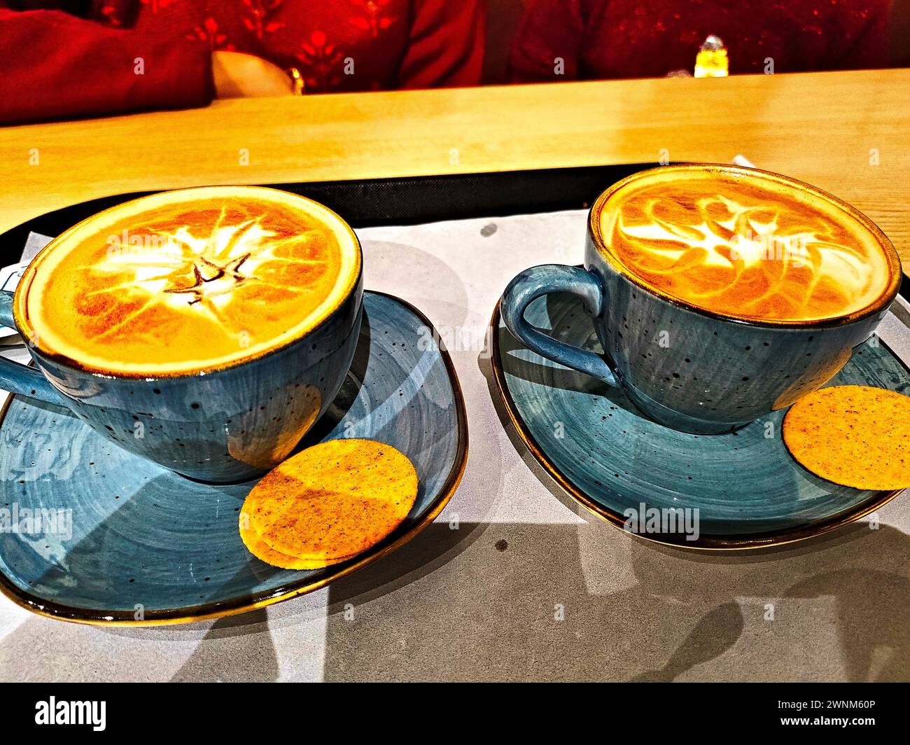 un paio di tazze di terra e un piatto contenente cappuchino serviti in un bar del tè Foto Stock