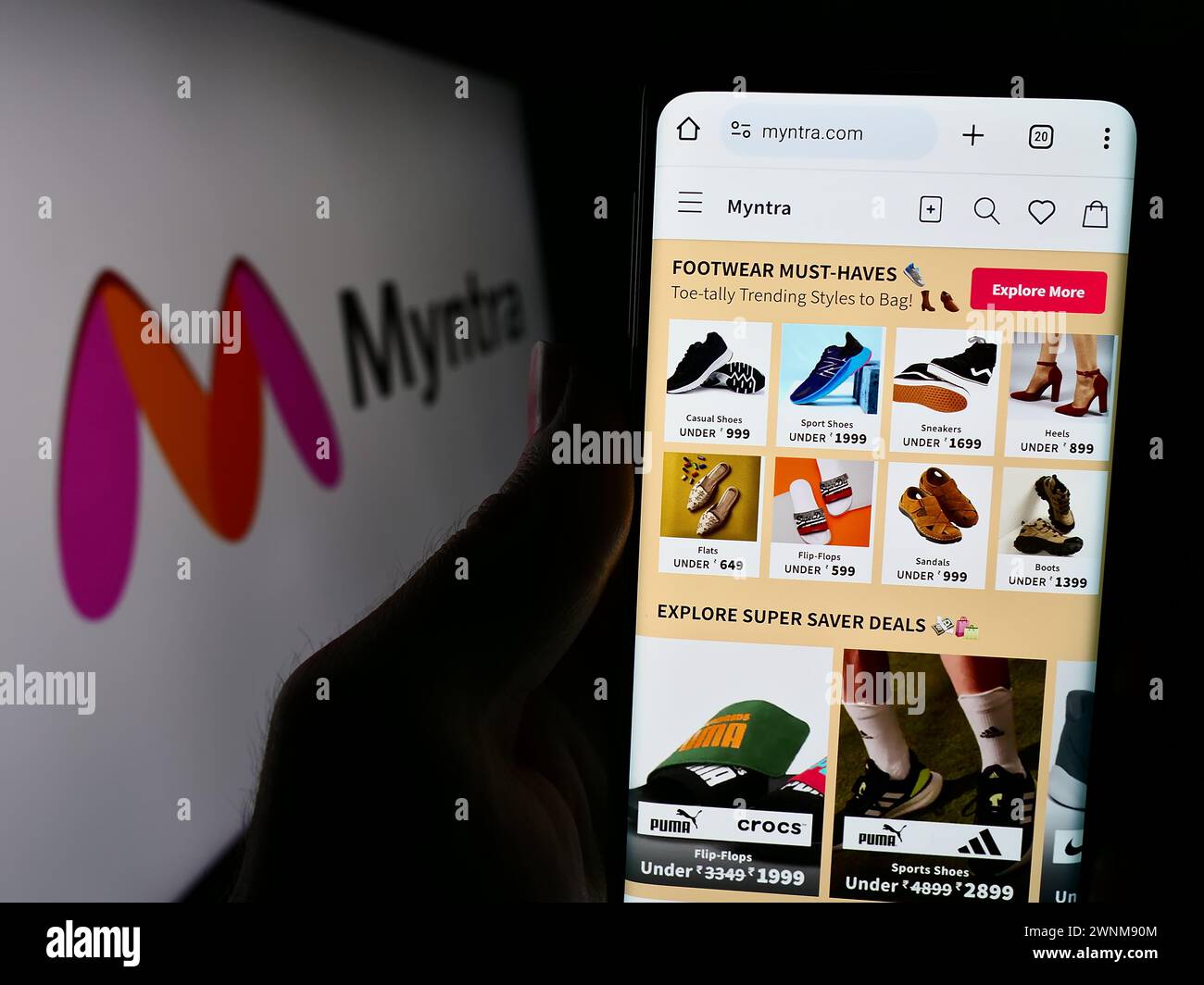 Persona che detiene un cellulare con pagina web della società indiana di e-commerce Myntra Designs Pvt. Ltd. Davanti al logo. Messa a fuoco al centro del display del telefono. Foto Stock