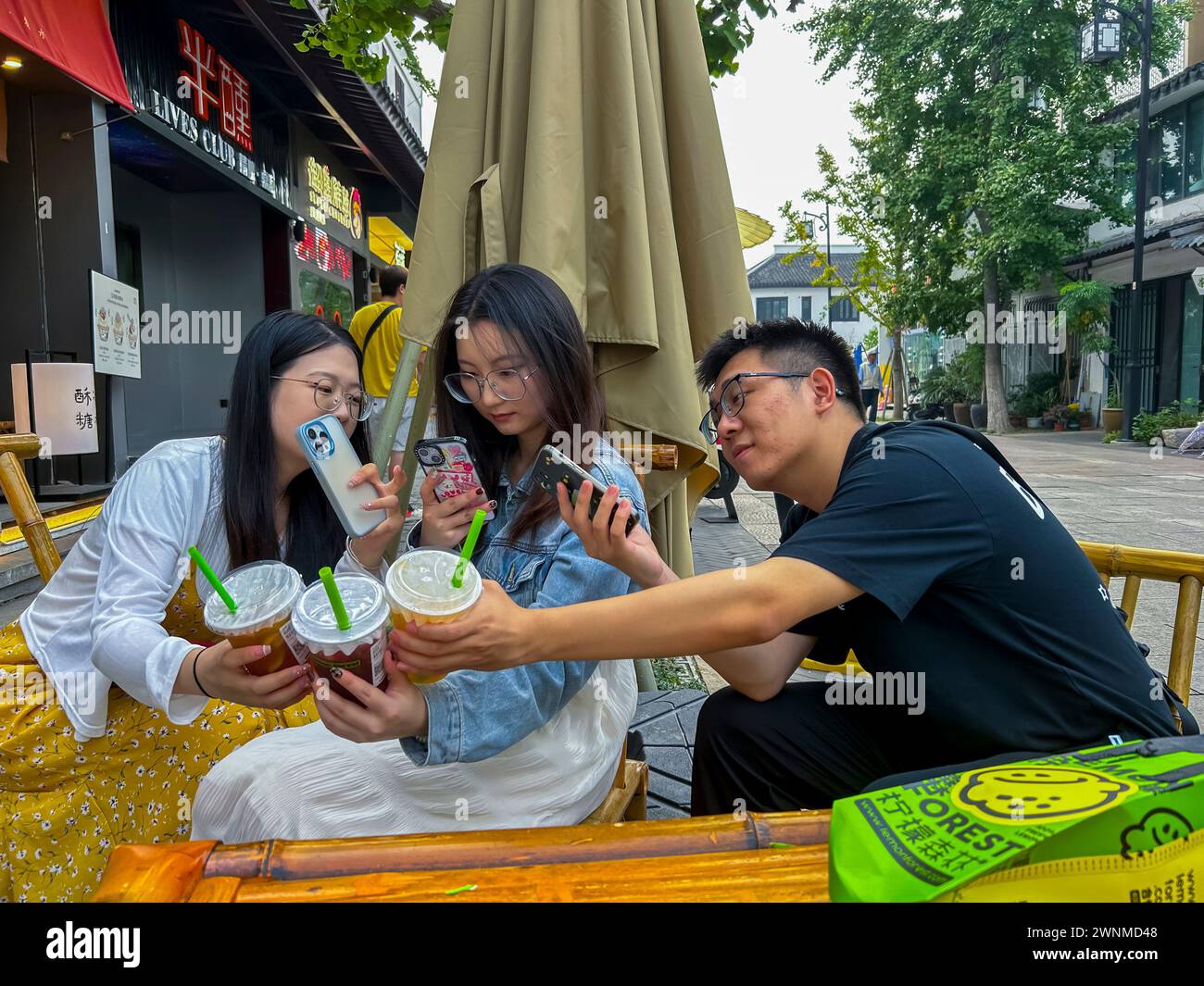 Suzhou, Cina, turisti cinesi, adolescenti che bevono bevande analcoliche, scene di strada, centro storico della città vecchia, scattare selfie su smartphone Foto Stock