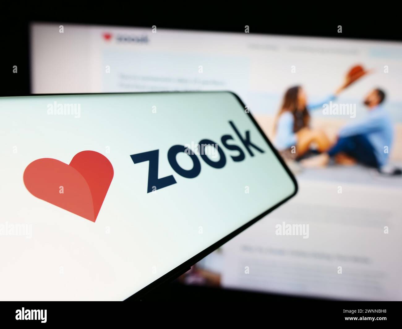 Smartphone con logo della società di piattaforme di incontri online Zoosk Inc. Di fronte al sito Web aziendale. Mettere a fuoco la parte sinistra del display del telefono. Foto Stock