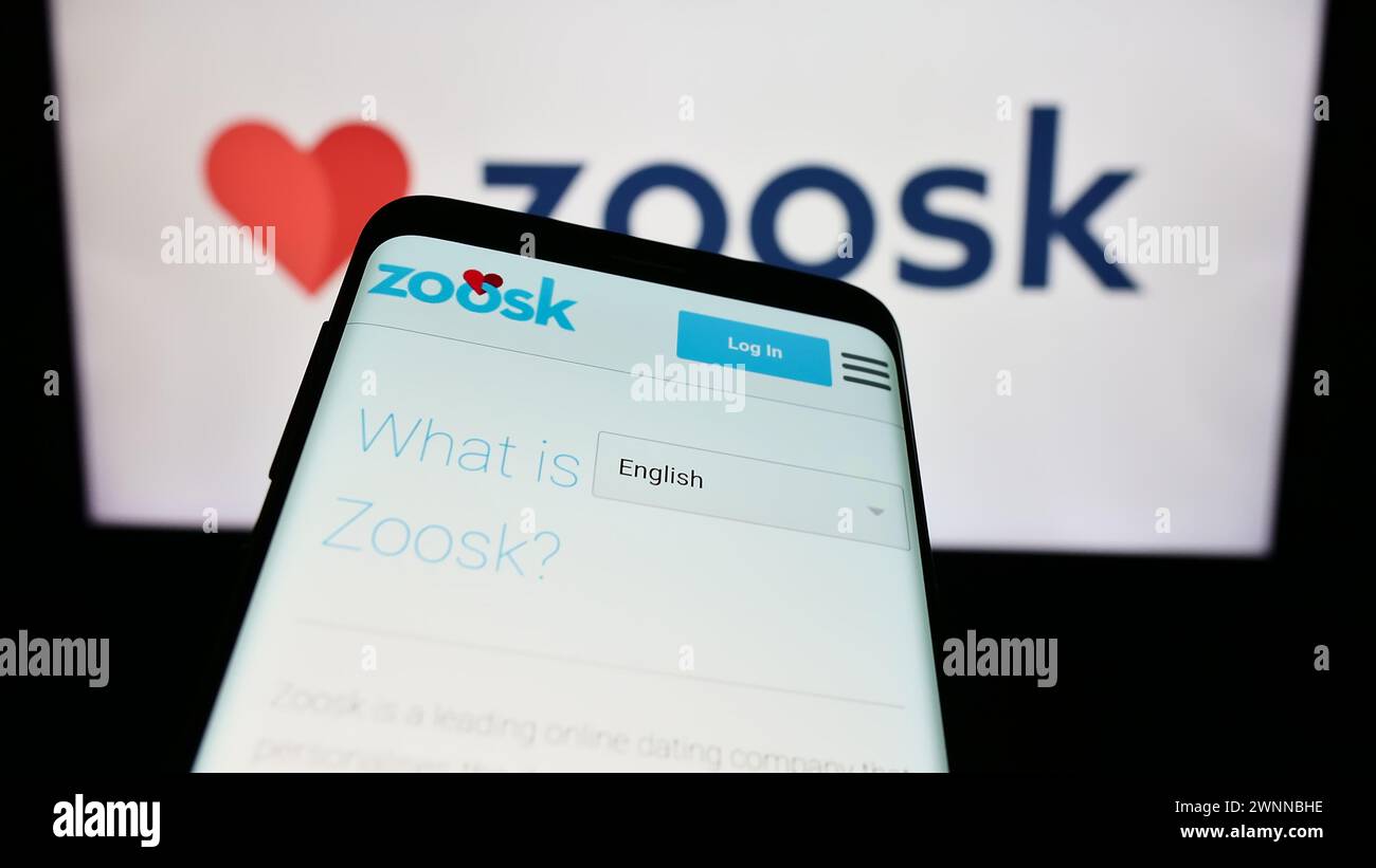 Telefono cellulare con sito web della società di piattaforme di incontri online Zoosk Inc. Davanti al logo aziendale. Mettere a fuoco in alto a sinistra sul display del telefono. Foto Stock
