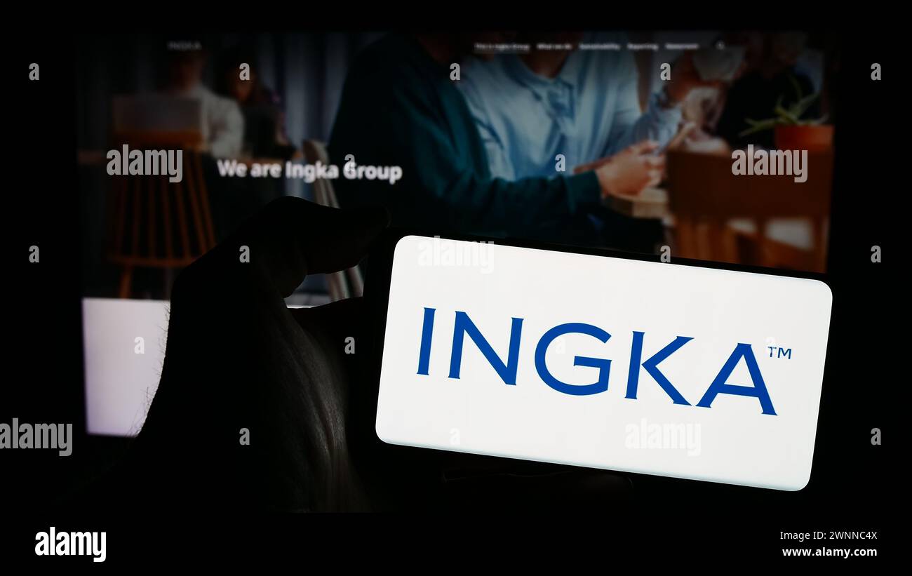 Persona che detiene un telefono cellulare con il logo della società olandese INGKA Holding BV di fronte alla pagina web aziendale. Mettere a fuoco il display del telefono. Foto Stock