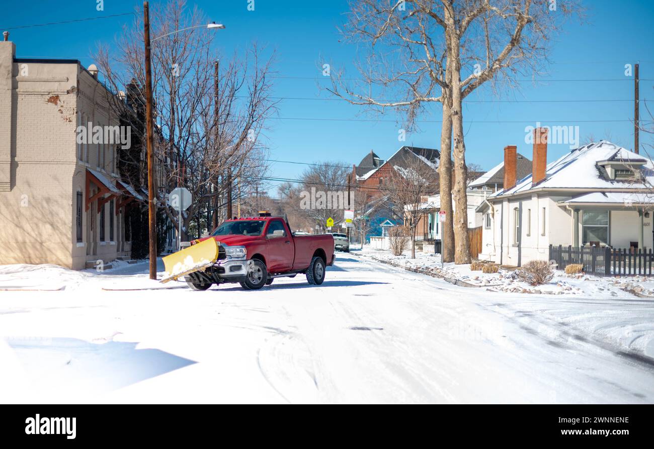 Il camion rosso spazzaneve ha eliminato la neve fresca dalla strada in un'area residenziale nel centro di Denver, Colorado. Foto Stock