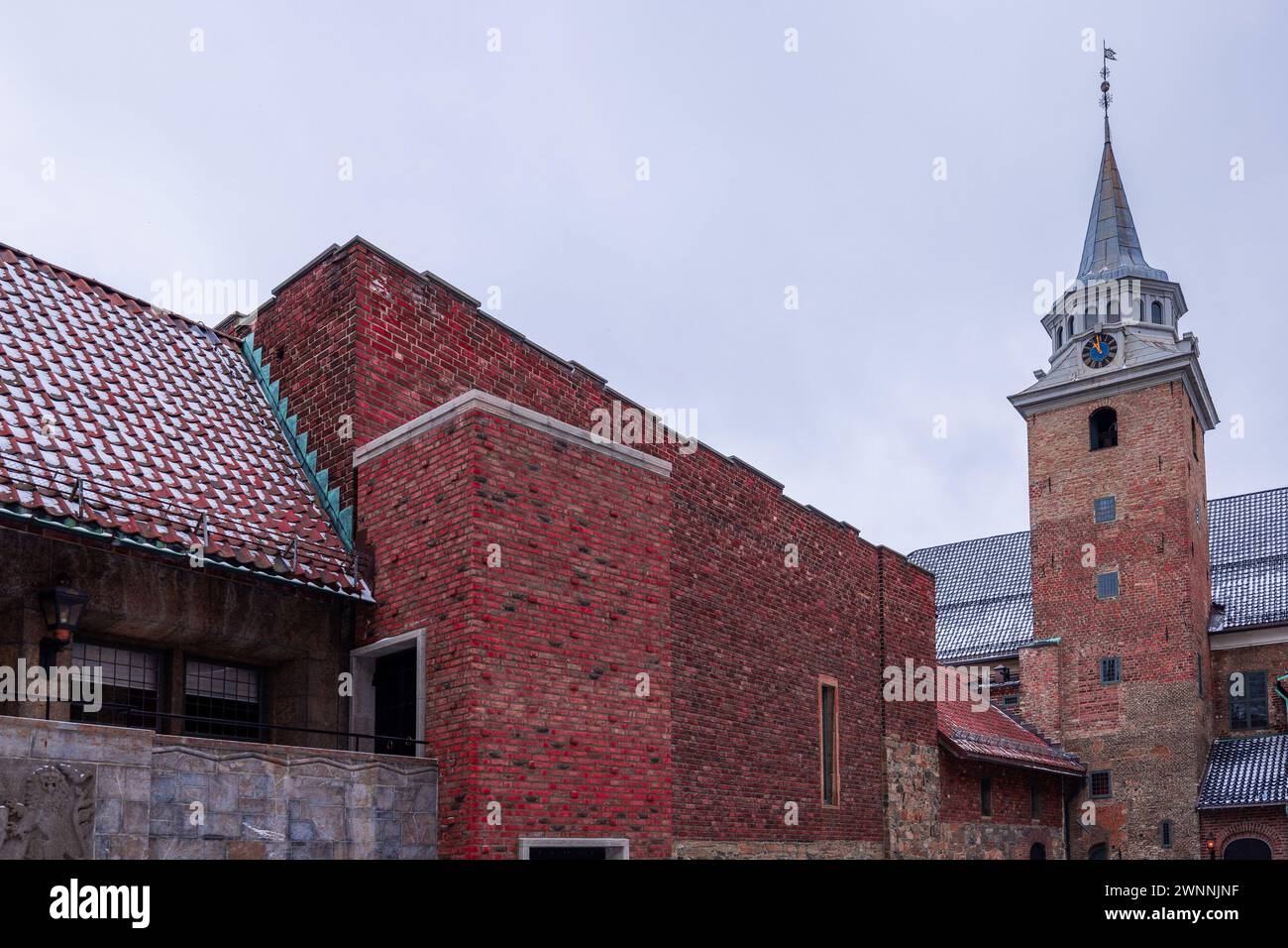 Chiesa e torre campanaria nel forte di akershus a Oslo in una fredda giornata invernale. Case visibili e grande campanile in mattoni rossi. La chiesa scandinava. Foto Stock
