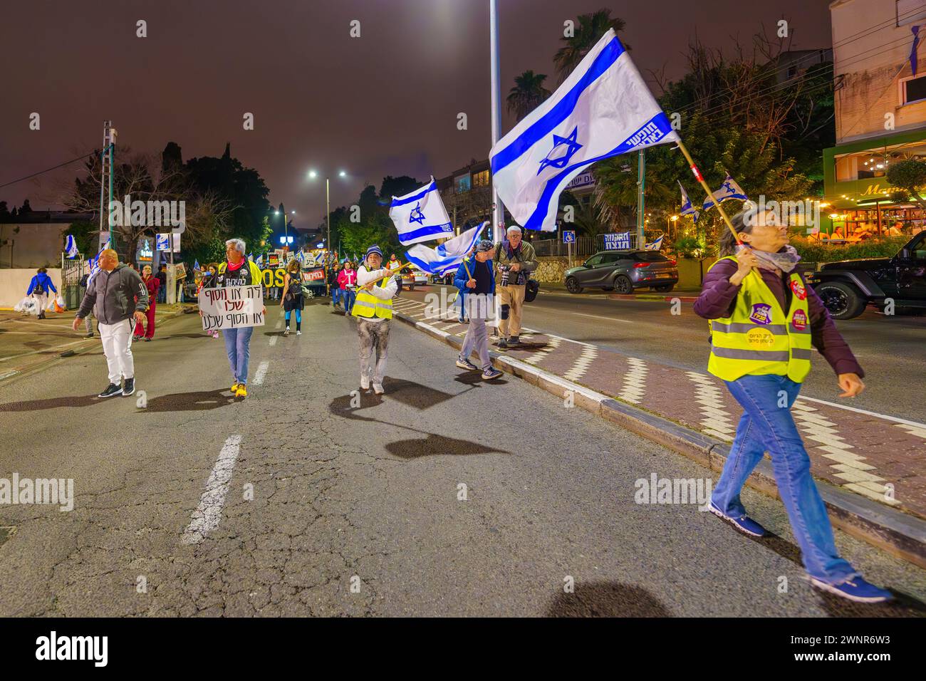 Haifa, Israele - 2 marzo 2024: La gente partecipa a una marcia di protesta, con vari segni e bandiere, contro il governo, che chiede nuove elezioni. Foto Stock
