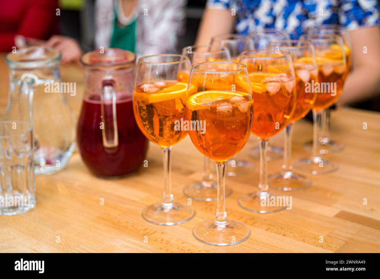 Rinfrescanti cocktail Aperol Spritz serviti in bicchieri da vino, guarniti con fette d'arancia, perfetti per una riunione sociale o una festa. Foto Stock