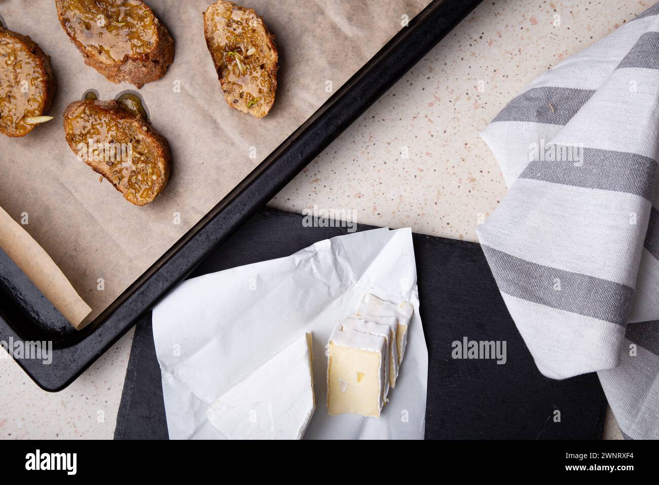 Formaggio Brie appena tagliato sull'ardesia con pane dorato sullo sfondo. Foto Stock