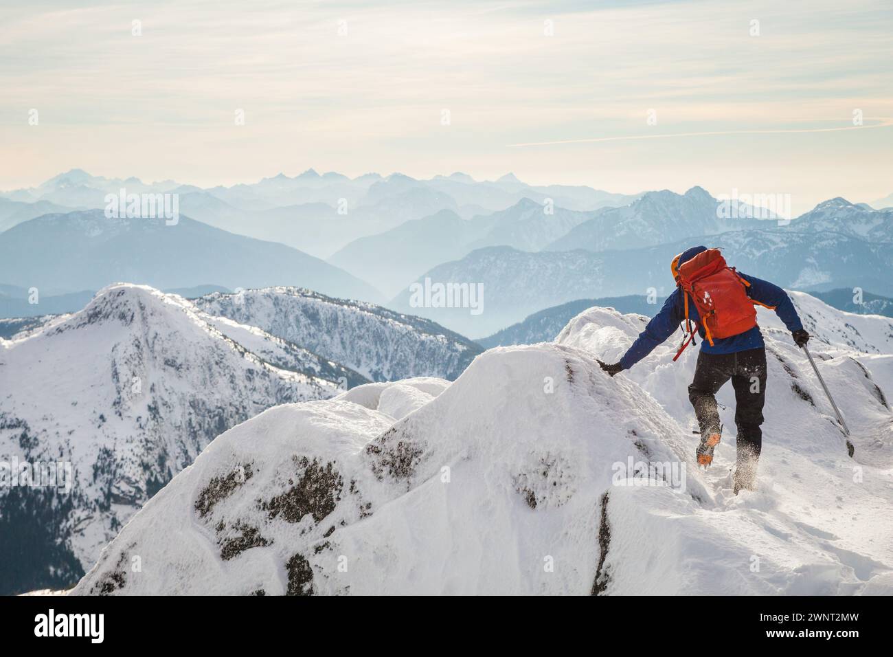 Mountaineer si cala con la mano sulla cresta della montagna Foto Stock