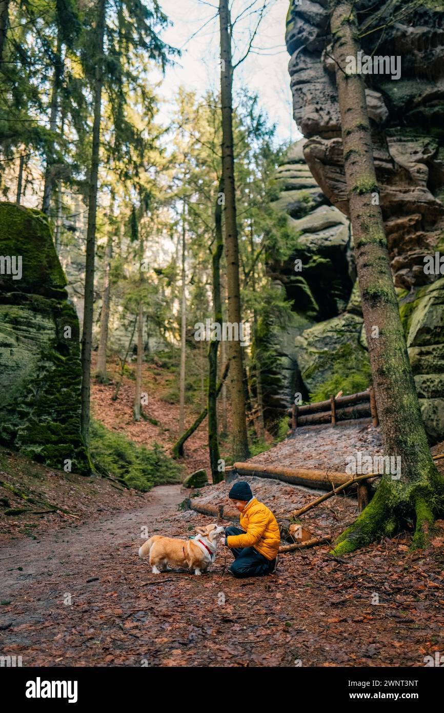 Un ragazzo e il suo cane corgi giocano insieme nella foresta Foto Stock
