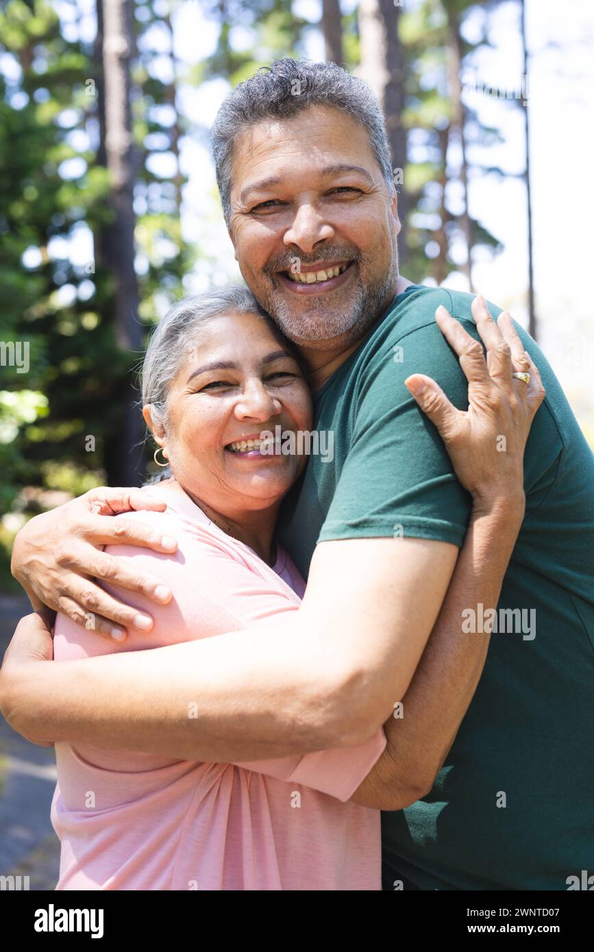 La coppia birazziale senior abbraccia l'aria calda all'aperto, entrambi sorridenti Foto Stock