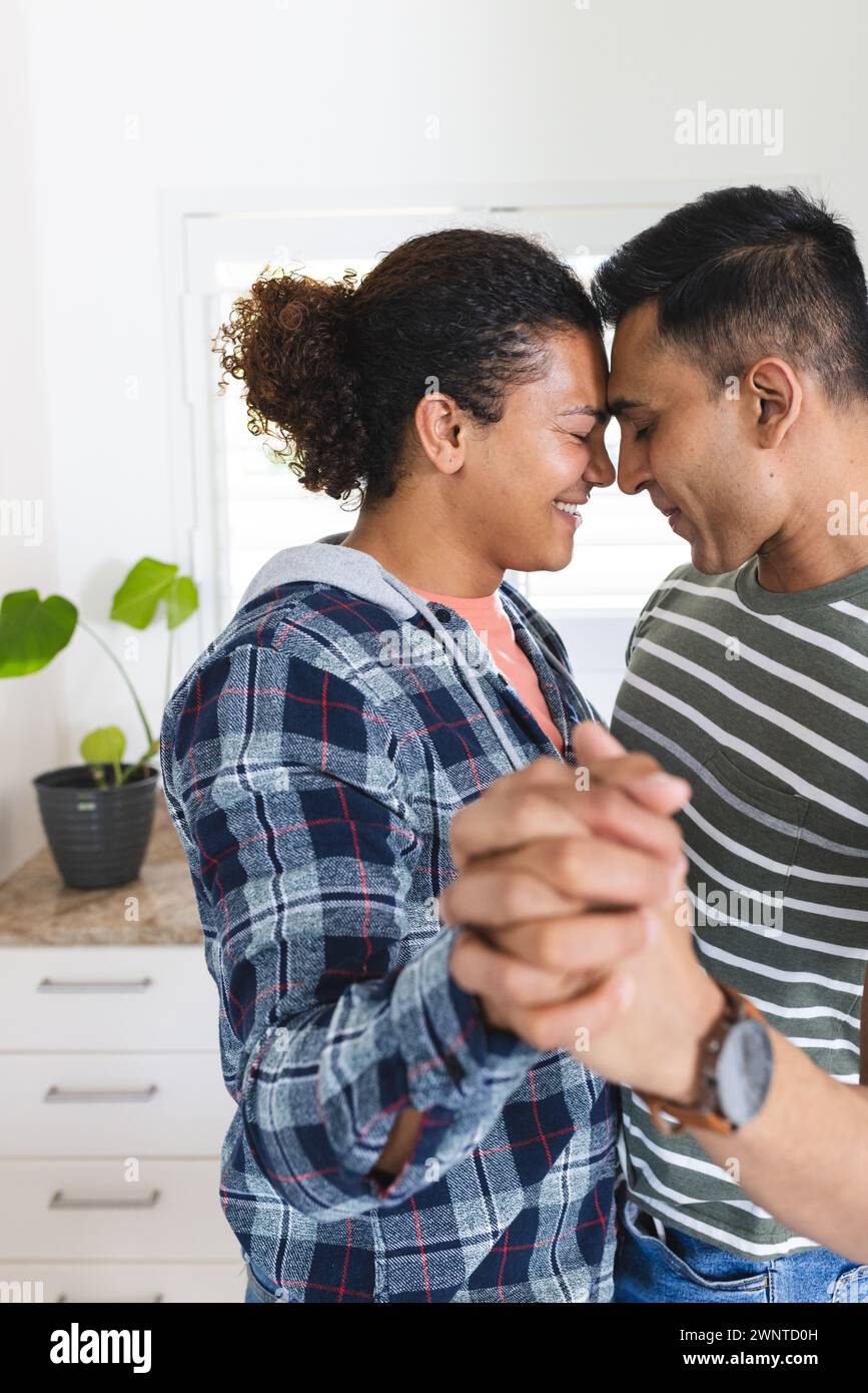 La coppia gay birazziale condivide un momento tenero, tenendosi per mano e sorridendo vicini Foto Stock