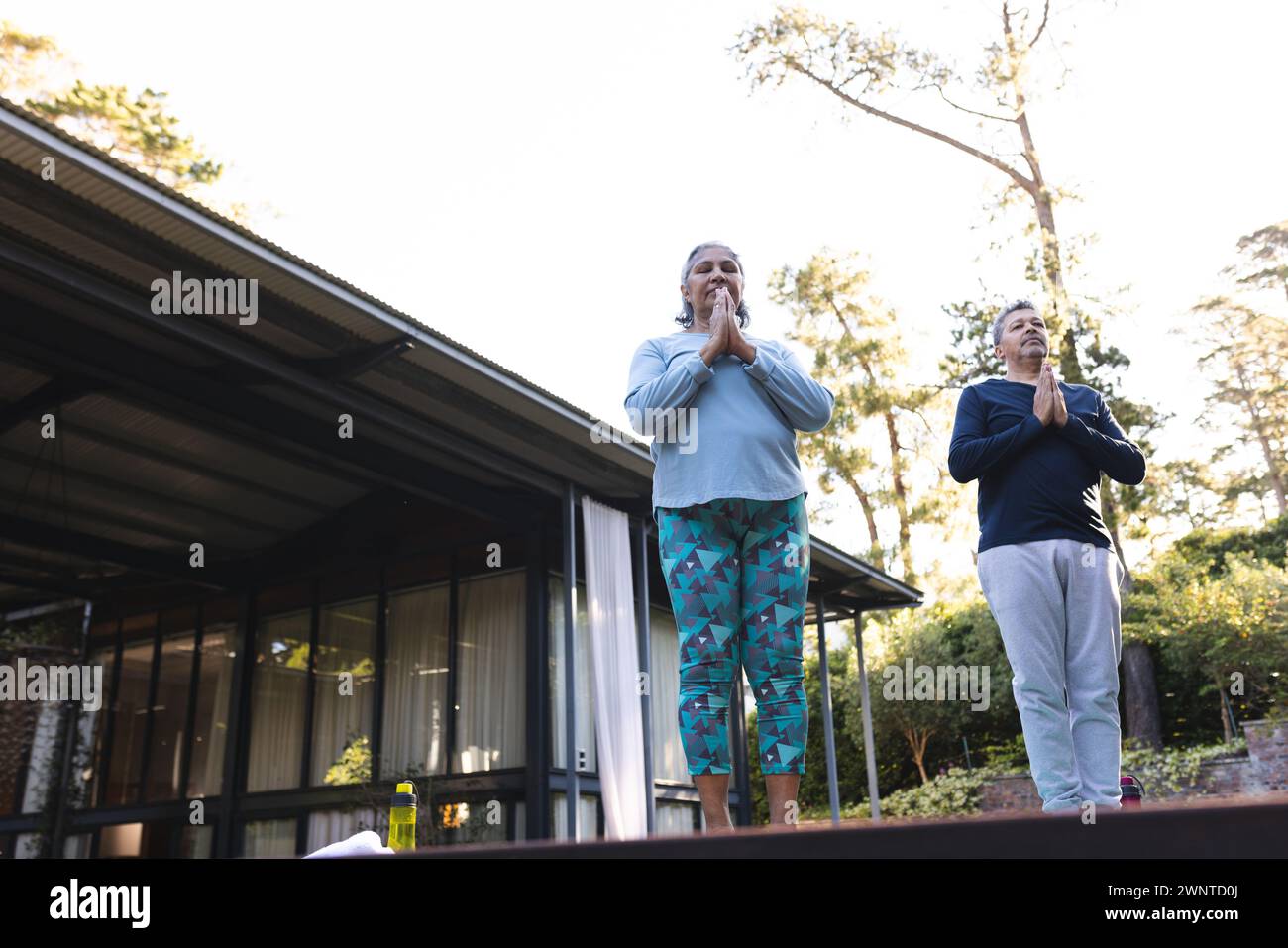 Donna birazziale senior e uomo birazziale praticano yoga all'aperto con spazio per copiare a casa Foto Stock