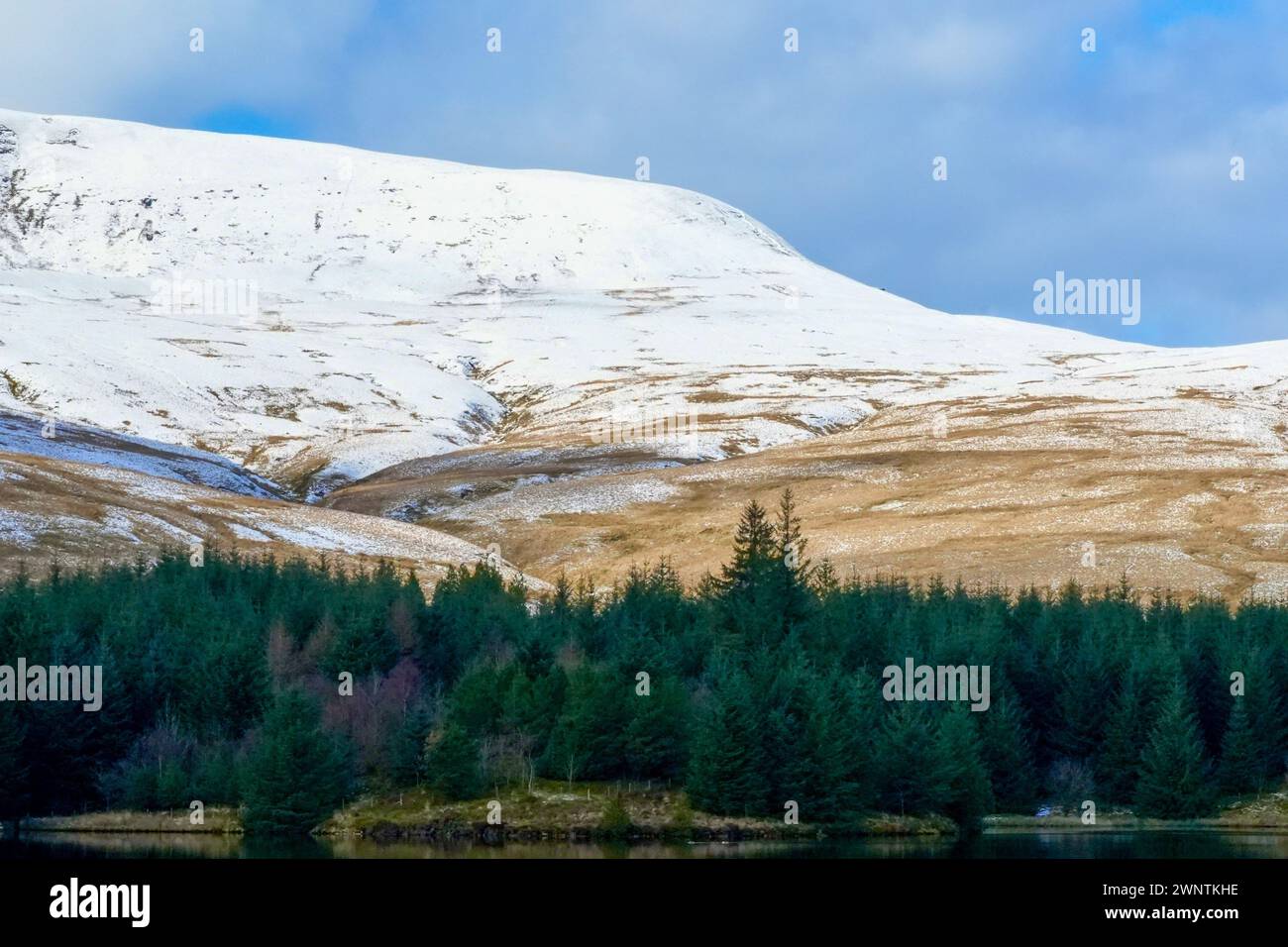 Paesaggio invernale e riflessi nell'acqua del bacino idrico gallese di Llwyn Onn, nel Brecon Beacons National Park. Montagne innevate ghiacciate Foto Stock