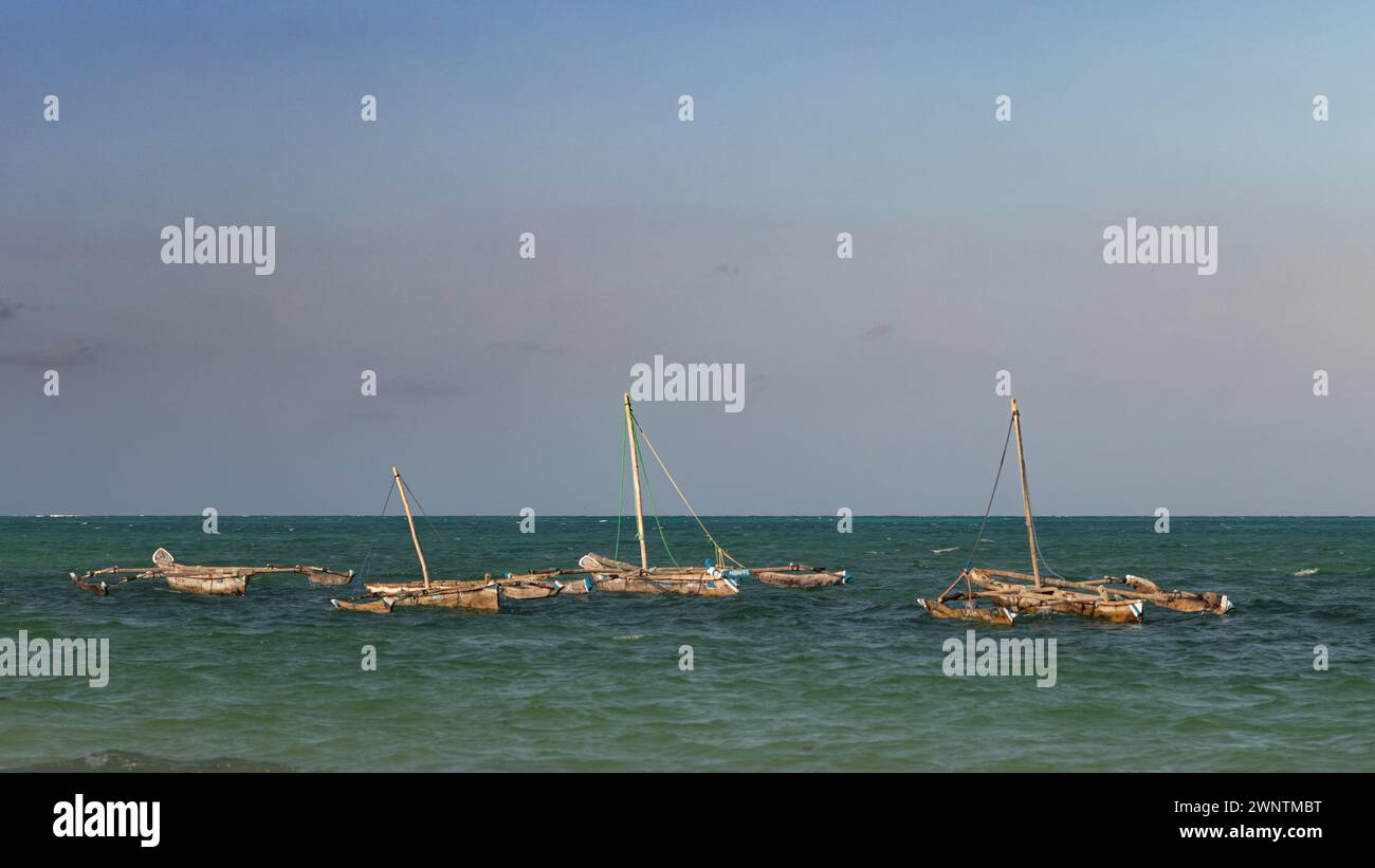 Quattro tradizionali barche in legno a dhow ormeggiate all'alta marea sulla spiaggia di Jambiani, Zanzibar, Tanzania Foto Stock