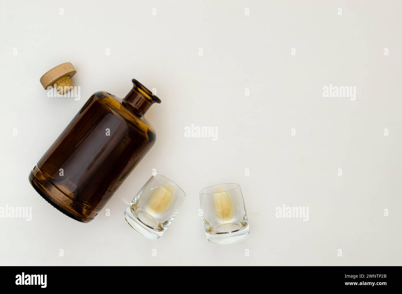 Due bicchieri per whiskey vuoti con una bottiglia di whiskey su sfondo grigio chiaro. Vista dall'alto. Foto Stock