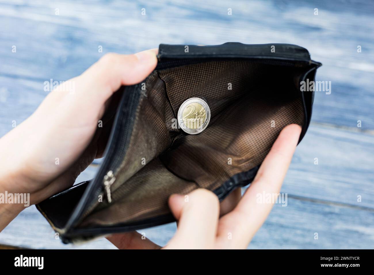 Un portafoglio con denaro e monete in mano su sfondo scuro, vista dall'alto. Una moneta in euro nel palmo della tua mano. Vista in prima persona. Foto Stock