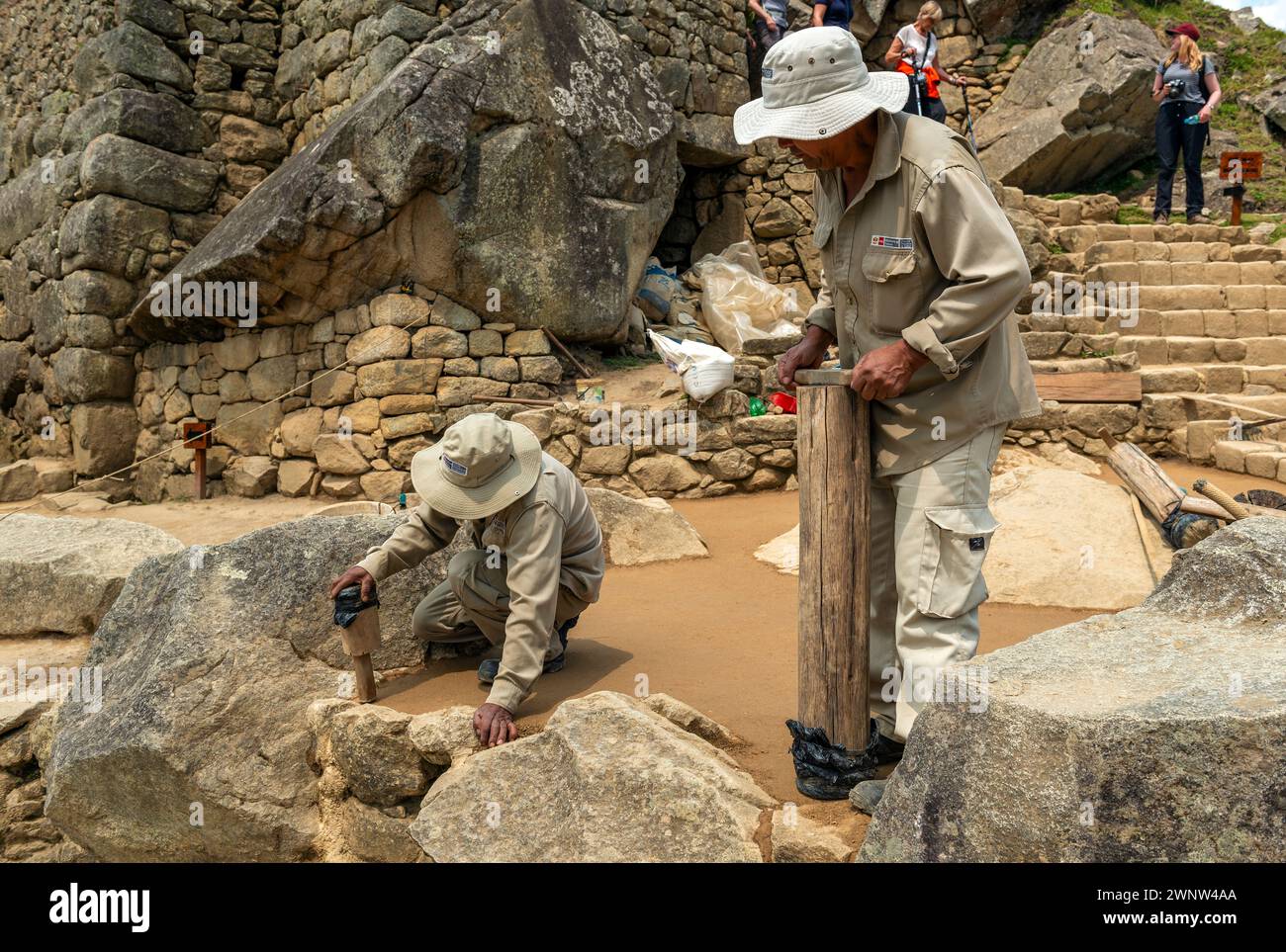 Operai peruviani che effettuano il restauro archeologico di un pavimento nella rovina Inca di Machu Picchu, Cusco, Perù. Foto Stock