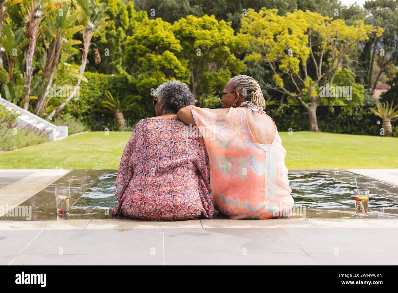 Donna afroamericana anziana e donna birazziale anziana seduto vicino, affacciato su un giardino Foto Stock