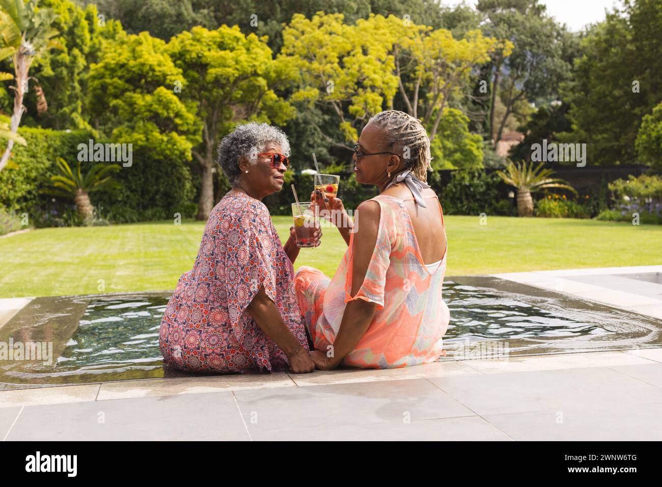 La donna afroamericana anziana e la donna birazziale anziana si godono un drink in piscina Foto Stock