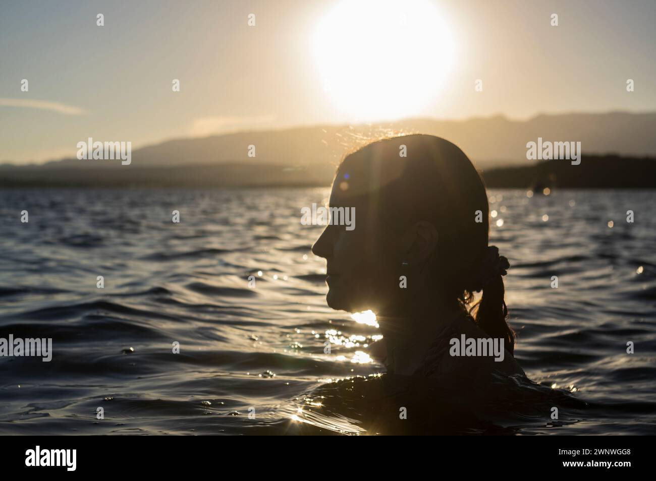 Donna che si raffredda nell'acqua di una diga Foto Stock