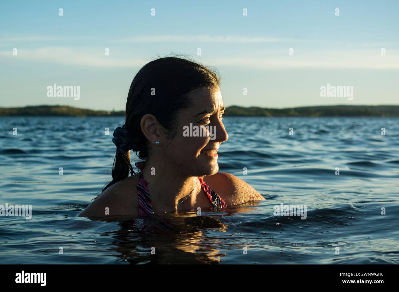 Donna che si raffredda nell'acqua di una diga Foto Stock