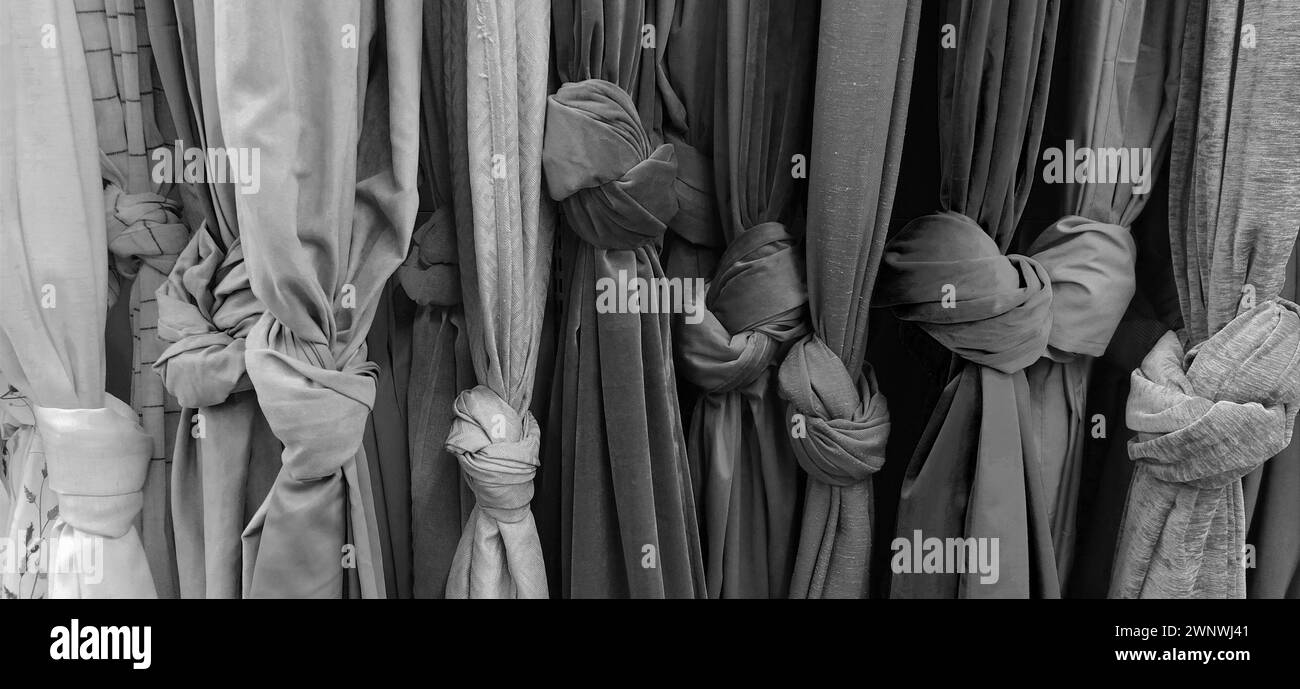 Tende e tessuti per tendaggi e decorazioni d'interni. Campioni di tessuti nel punto vendita sono appesi verticalmente e legati a nodi. Tende nella Foto Stock