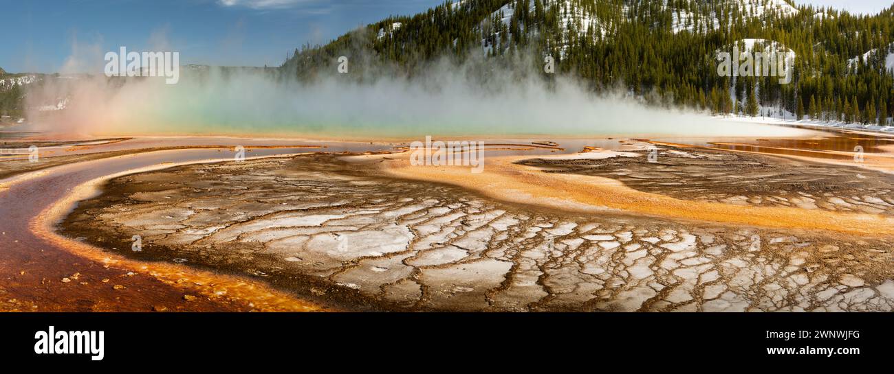 La grande sorgente prismatica che si affaccia su Yellowstone mostra colori vivaci di una sorgente termale calda con depositi minerali e un arcobaleno di vapore sullo sfondo Foto Stock